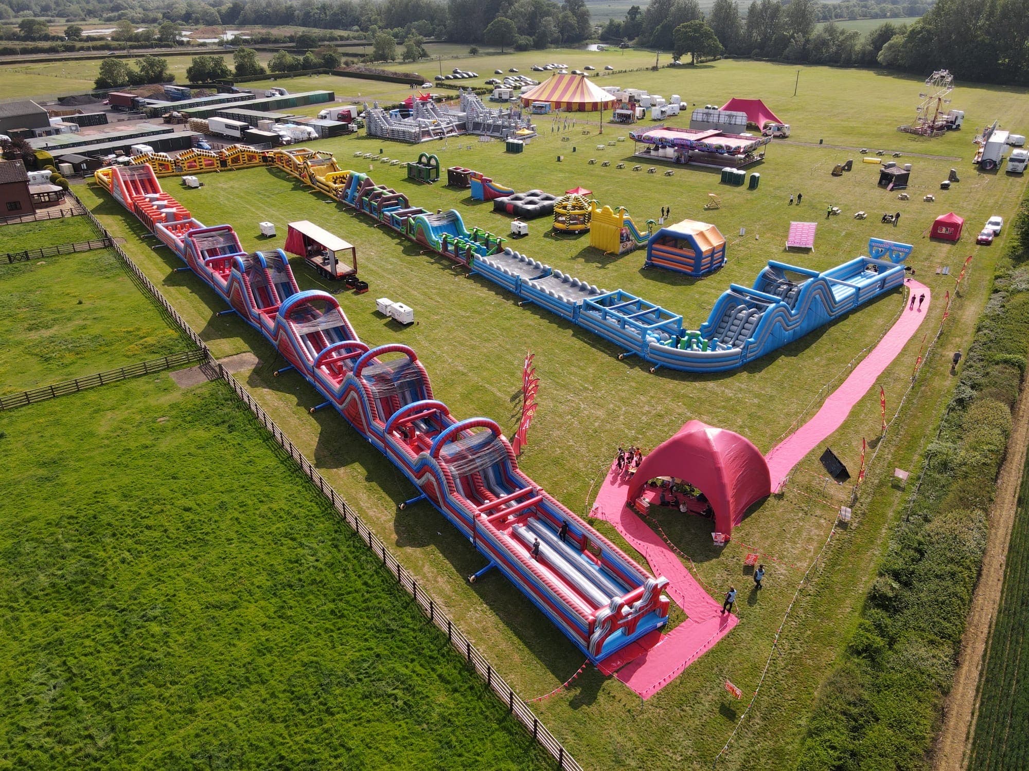 Labyrinth2022 Aerial view of a large outdoor inflatable obstacle course event on a grassy field.
