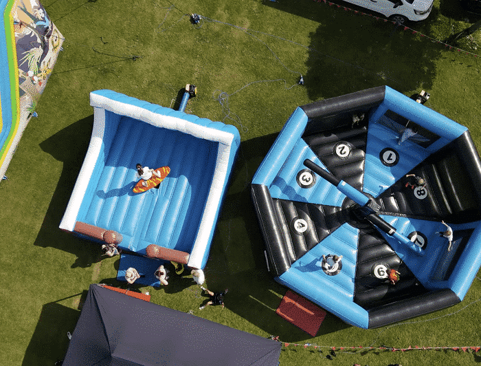 MegaFamilyFest-Hire Aerial view of inflatable rides at an outdoor event, with people participating and watching.