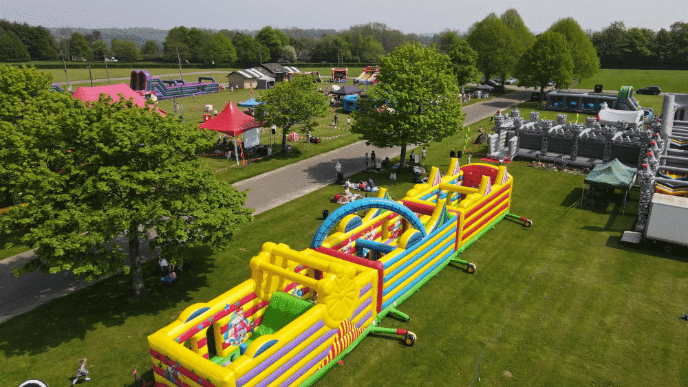 MegaFunFamilyFest Colorful inflatable obstacle courses and tents set up in a park for a family festival event.