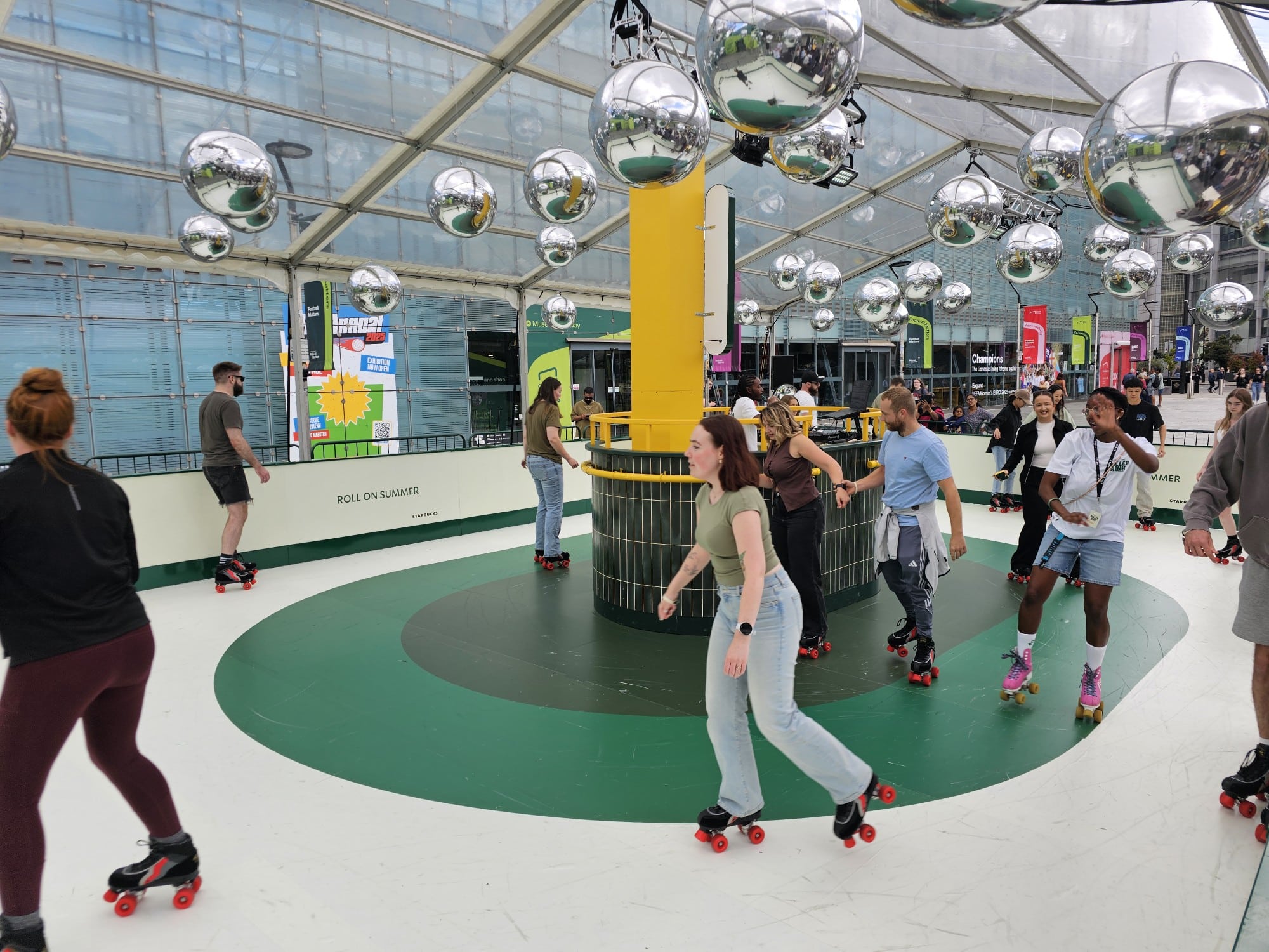 People roller skating under hanging disco balls in an indoor rink.