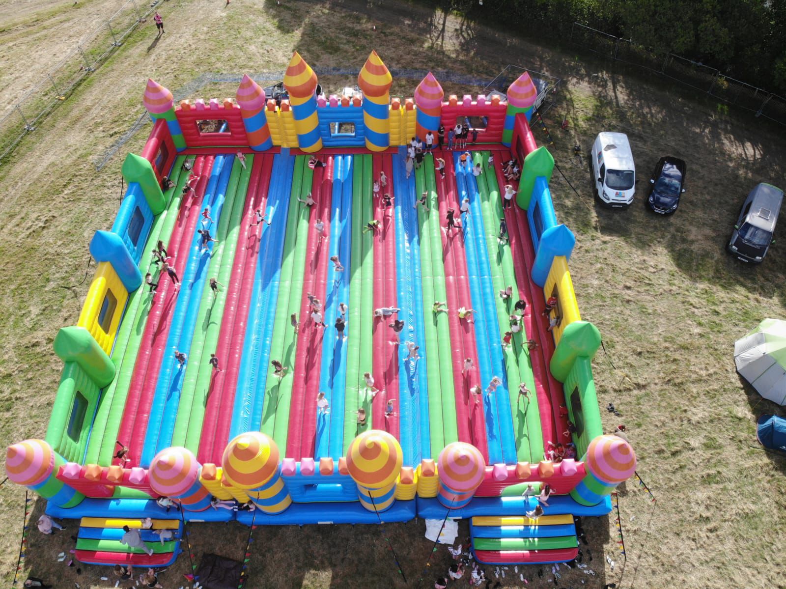 Aerial view of a large colorful inflatable bouncy castle set up outdoors with people inside.