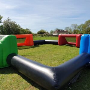 Inflatable football arena with four colorful goals on a grassy field.