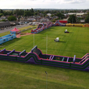 Large inflatable obstacle course set up on a grassy field, viewed from above.