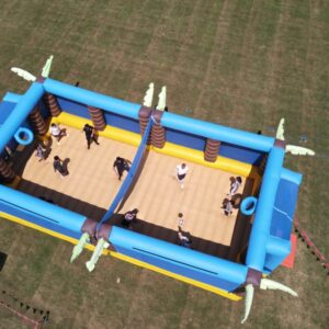 Aerial view of people playing inside an inflatable volleyball court on grass.