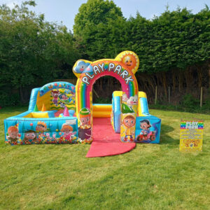 Colorful inflatable play park set up on grass with cartoon characters and a sign nearby.