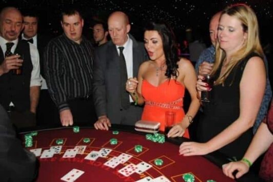 Group of people gathered around a blackjack table, watching the game with excited expressions.
