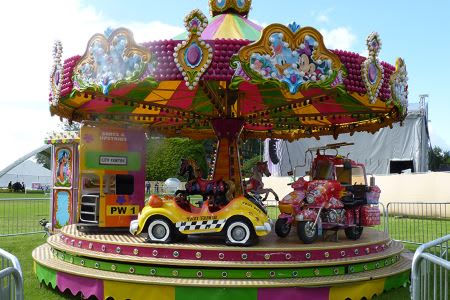 Colorful children's carousel ride with toy vehicles at a fun fair.
