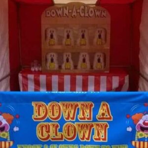 Red and white Down-A-Clown carnival stall with clown targets and a blue sign.