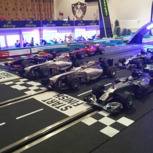 Model Formula 1 cars lined up on a slot car racing track at the start/finish line.